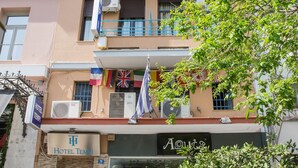 A hotel with multiple balconies, a storefront with a sale sign, and flags. - Tempi Hotel (Athens)