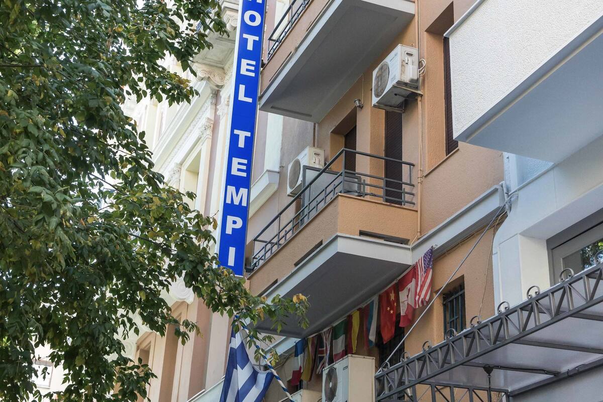 A multi-story hotel with balconies, air conditioning units, and a sign reading "HOTEL TEMPI".