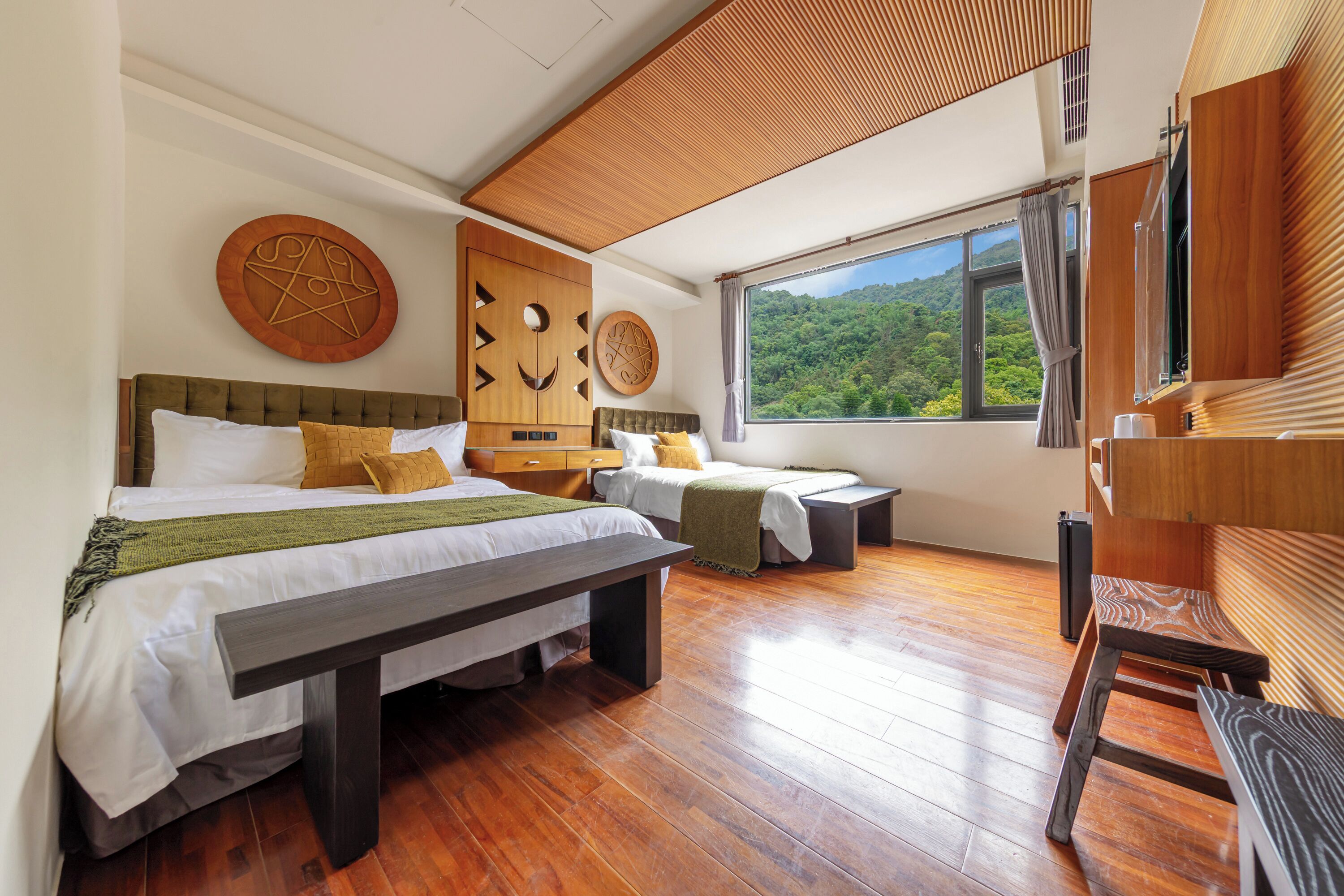 Een moderne slaapkamer met twee bedden, een houten plafond en een groot raam met uitzicht op een bos.