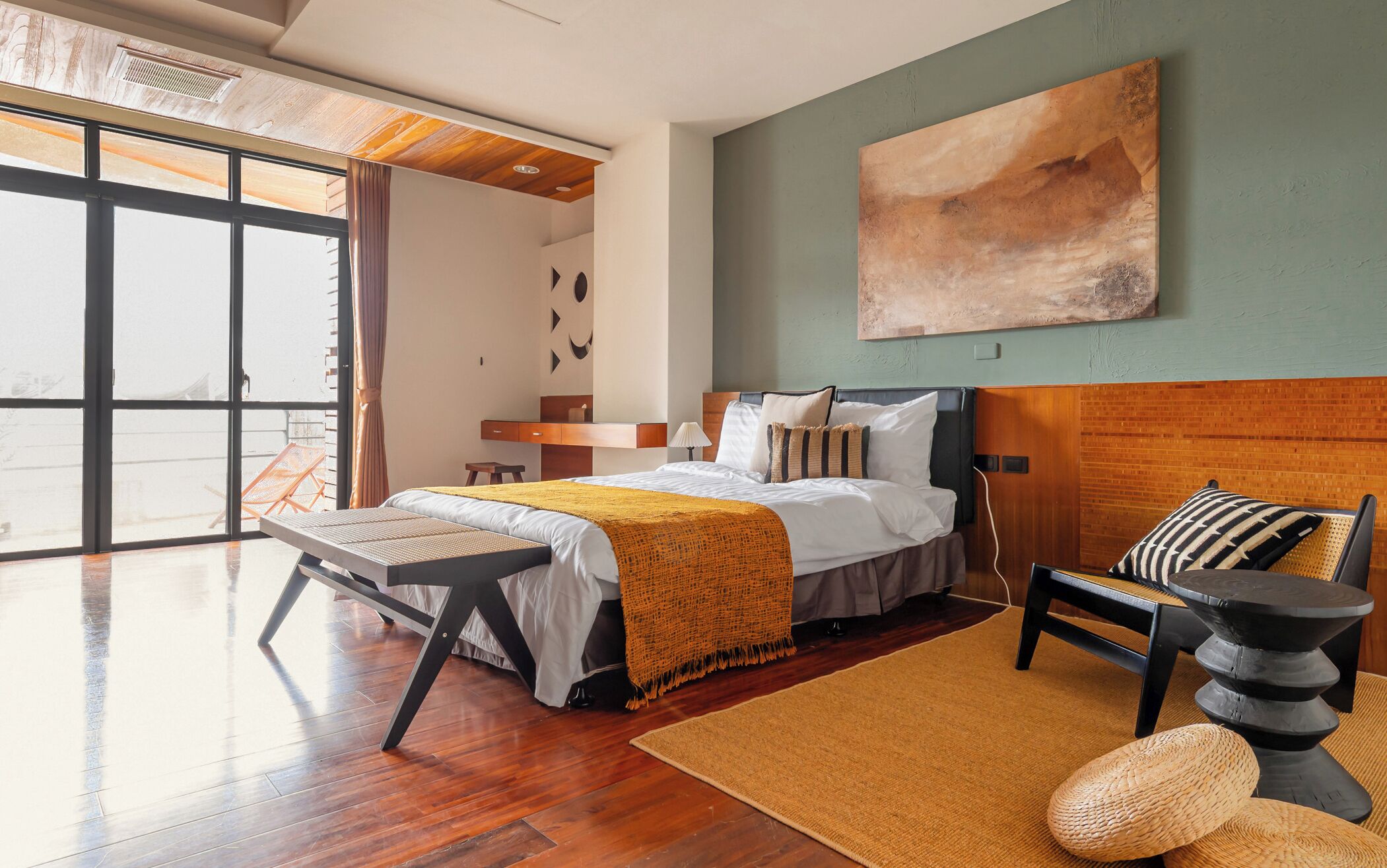 A modern bedroom with a large bed, a view of the outdoors, and a wooden ceiling.