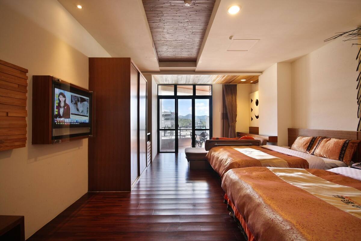 Une chambre d’hôtel avec un grand lit, une télévision, un balcon avec vue et un plancher en bois.