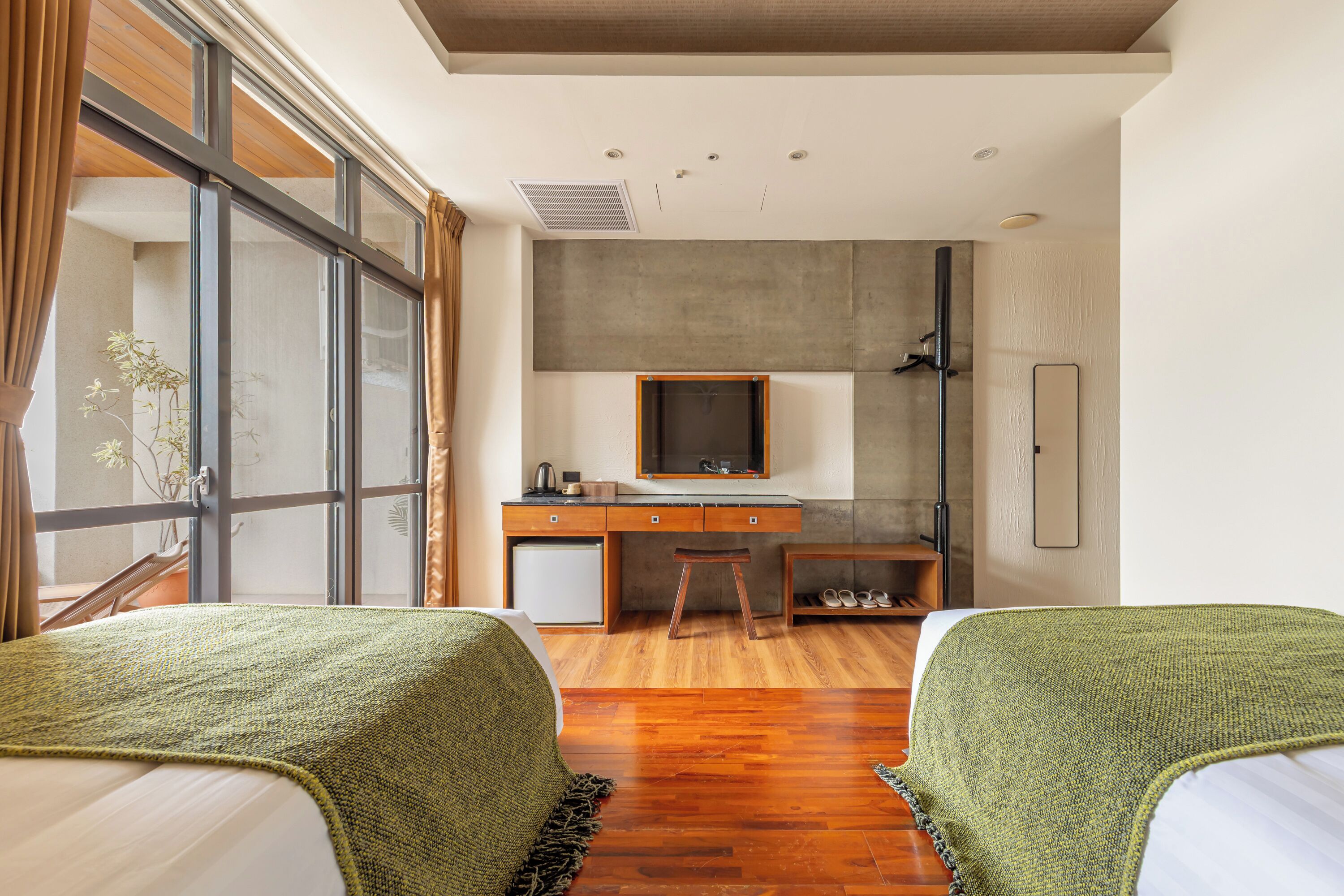 Un dormitorio con dos camas, un escritorio, una silla y un ventanal grande.
