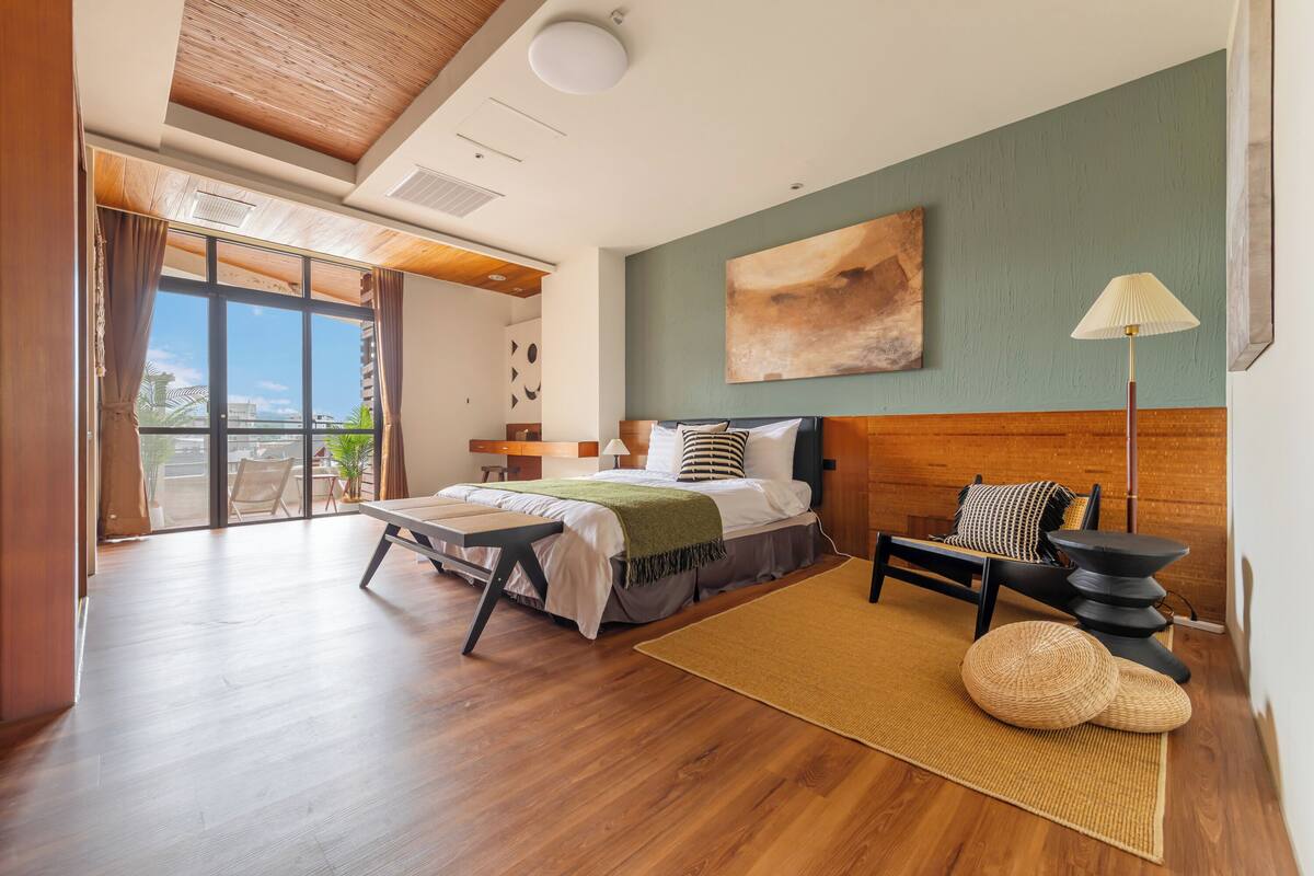 Une chambre à coucher moderne avec un lit, une chaise, une lampe et une vue sur l’extérieur.