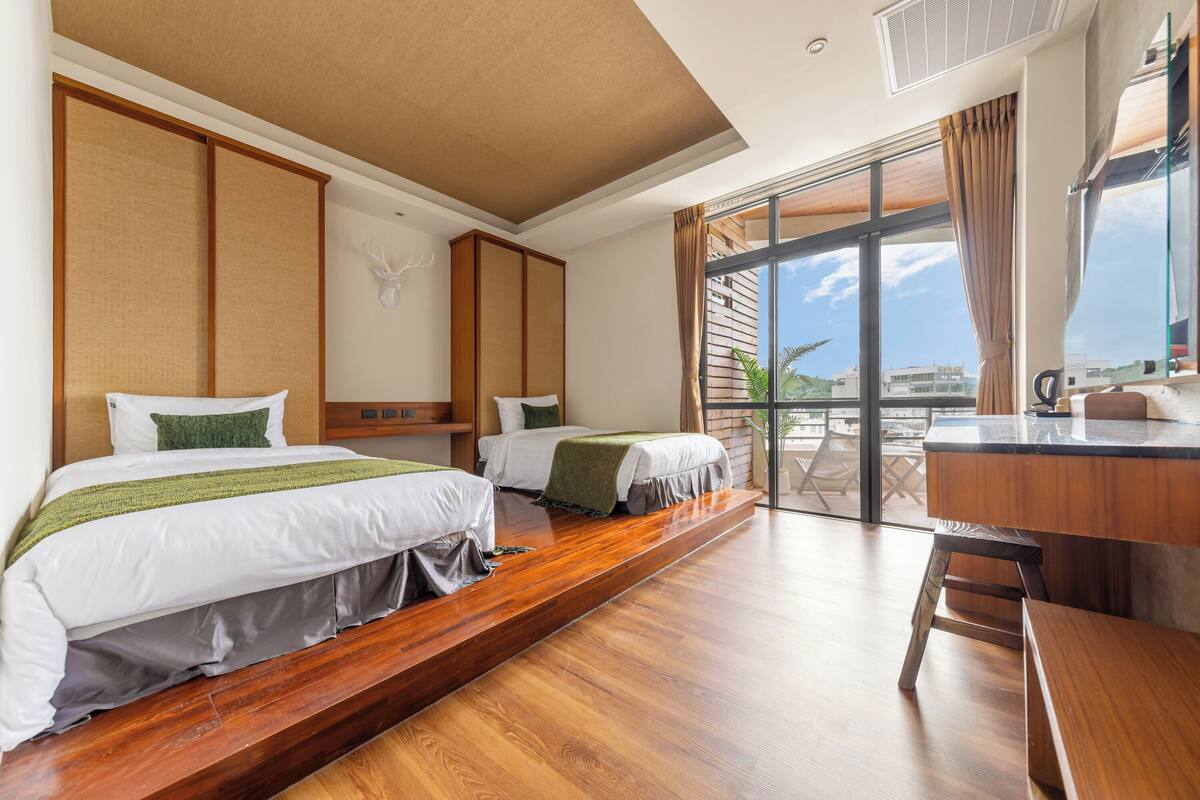 Une chambre d’hôtel avec deux lits, un plancher en bois, un balcon avec vue et une kitchenette.