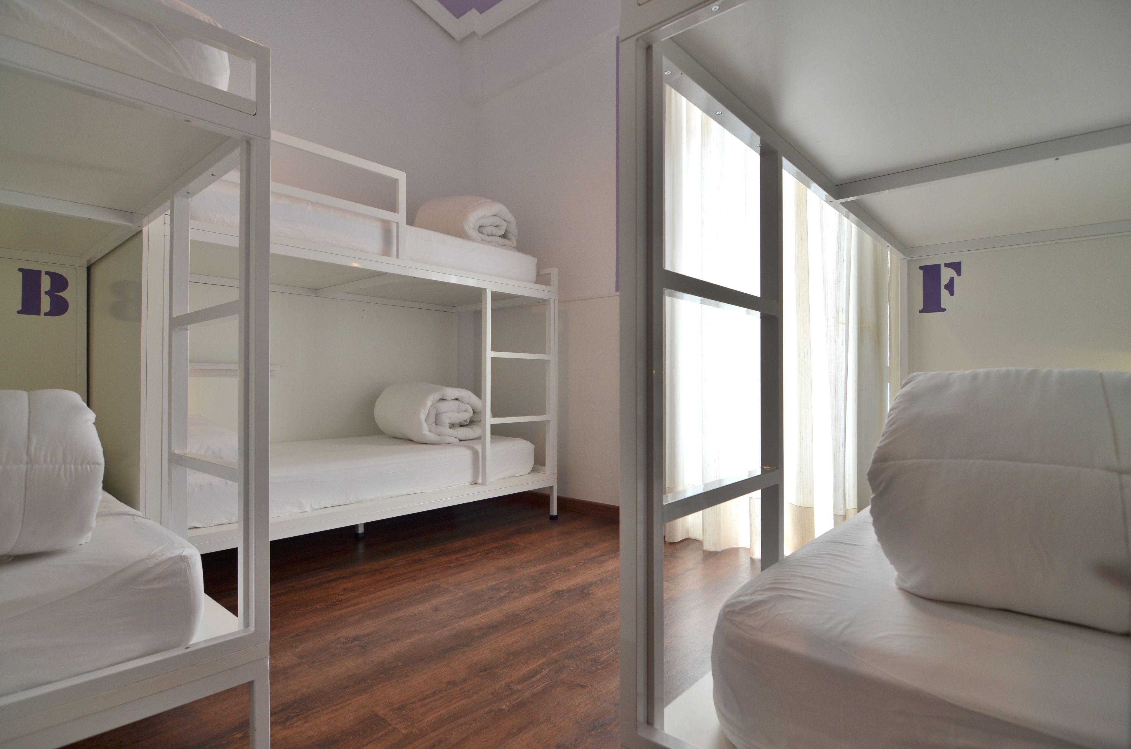 Een kamer met stapelbedden, een witte kledingkast en een groot raam met gordijnen.