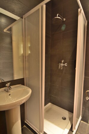 A modern bathroom with a shower enclosure, a sink, and a mirror. - Far Home Atocha (Madrid)