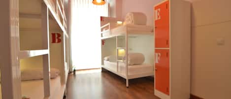 A dormitory room with bunk beds, a wardrobe, and a hanging light fixture.