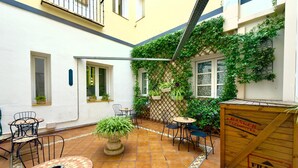 A courtyard with tiled flooring, outdoor seating, potted plants, and a wooden crate labeled "FRAGILE".