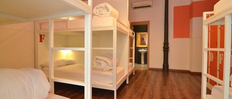 A dormitory room with bunk beds, a sink, and a mirror.