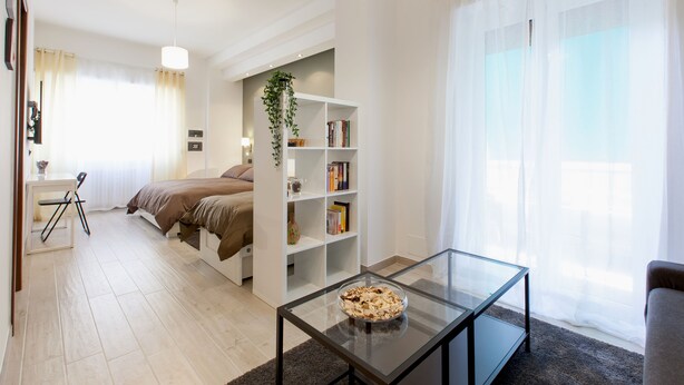 Une chambre à coucher moderne avec un lit, une table de chevet et une bibliothèque.