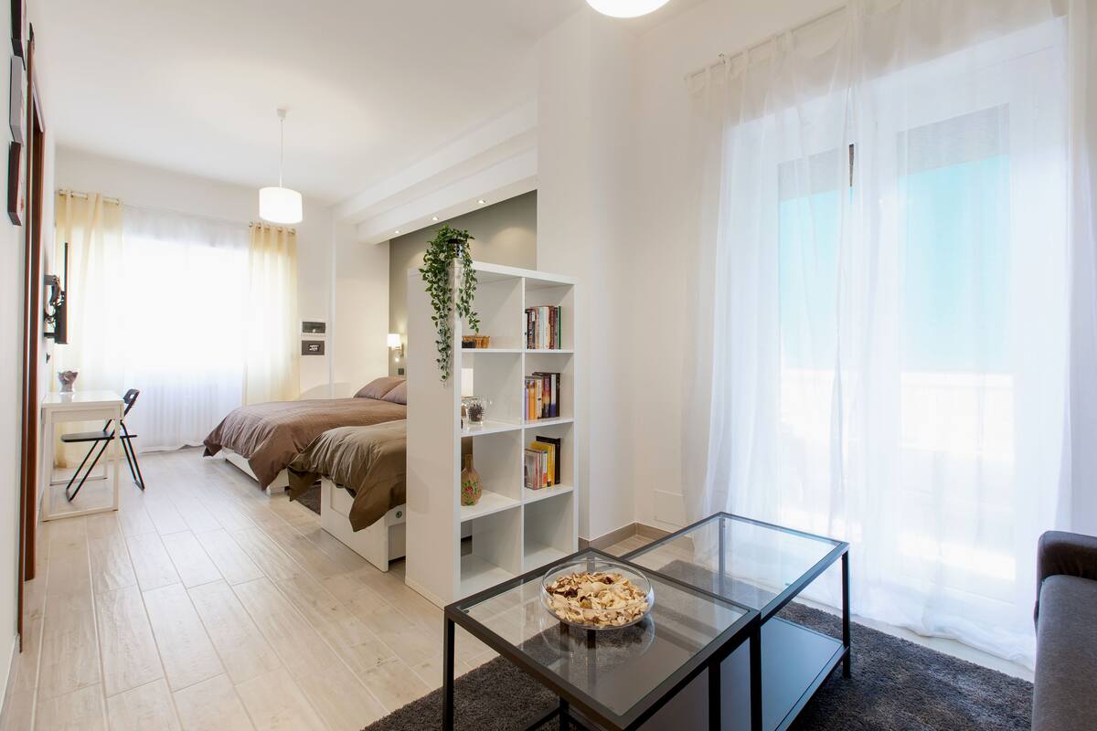 A modern bedroom with a bed, bedside table, and a bookshelf.