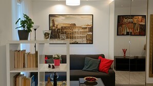 Un salon moderne avec un canapé noir, une table basse, une bibliothèque et un grand tableau accroché au mur.