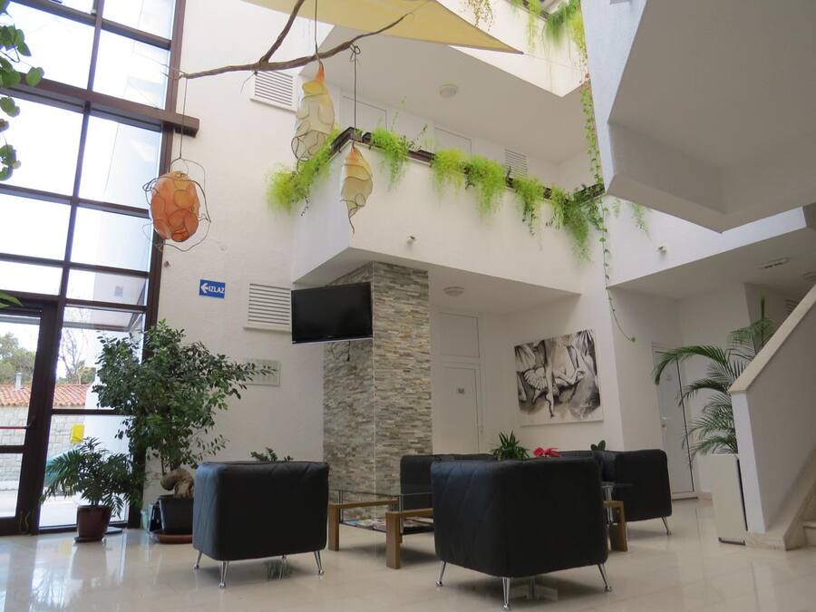 Un vestíbulo espacioso con techos altos, ventanas amplias y una decoración que combina elementos modernos y naturales, como plantas colgantes y obras de arte.