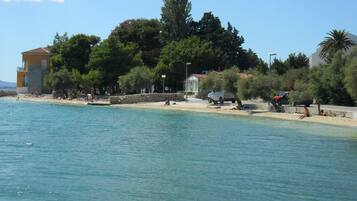 A coastal area with a beach, buildings, and trees.