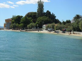A coastal area with a beach, buildings, and trees.