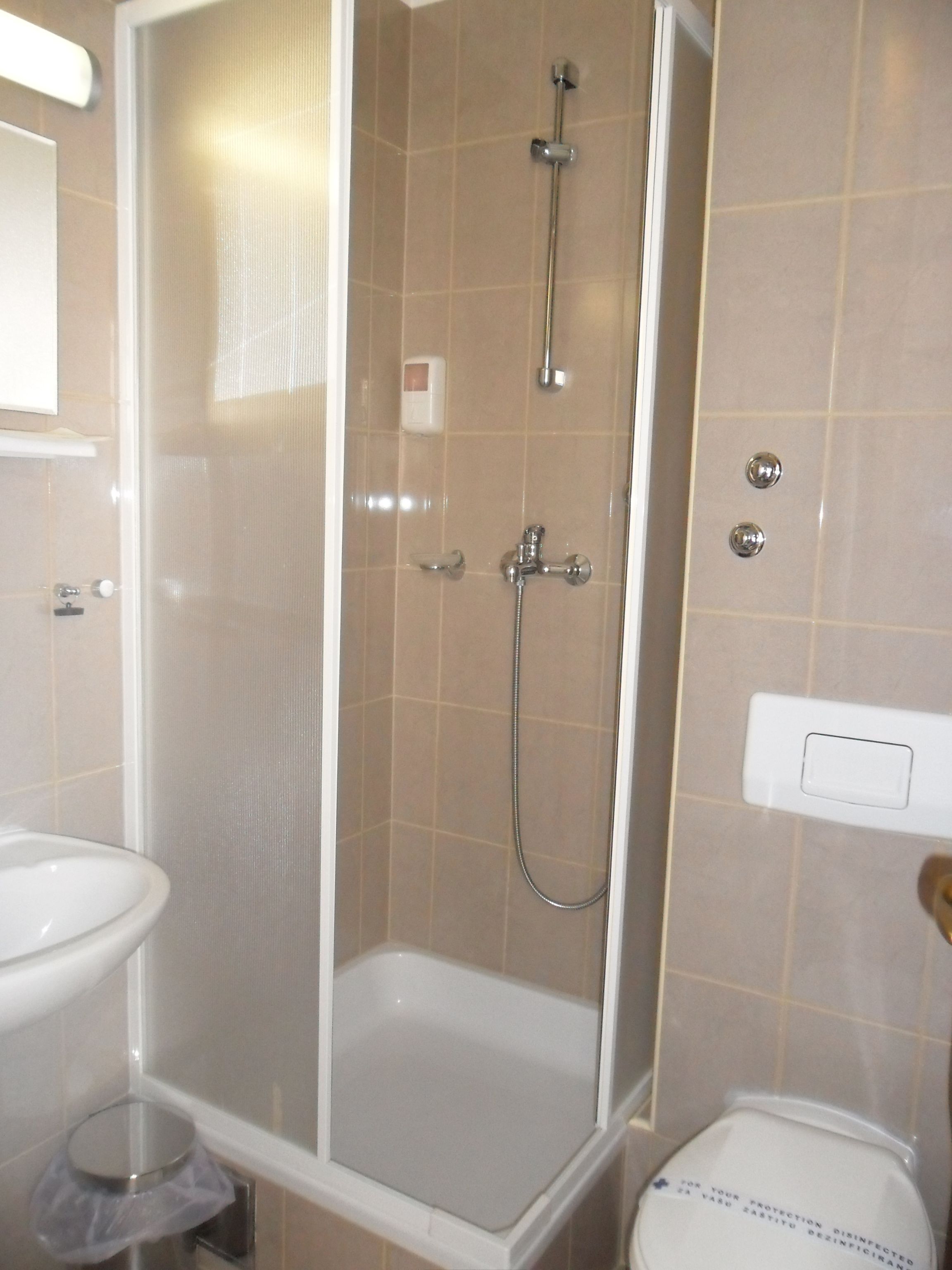 Un baño con cabina de ducha, inodoro y lavamanos.