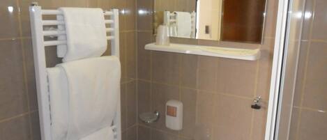 Un baño con un lavamanos blanco, un perchero, un espejo y un dispensador de jabón.