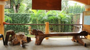 A wooden bench with a unique design, situated in a covered outdoor area with a view of lush greenery. - Villa Manuel Tourist Inn (Puerto Princesa)