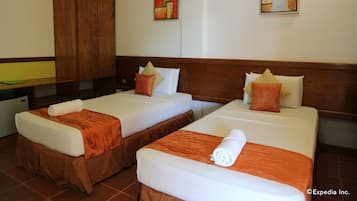 Two single beds with brown headboards, white linens, and orange throw blankets.