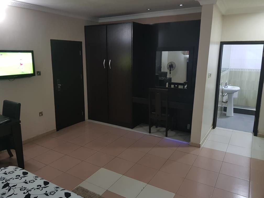 A bedroom with a bed, wardrobe, desk, and a TV.