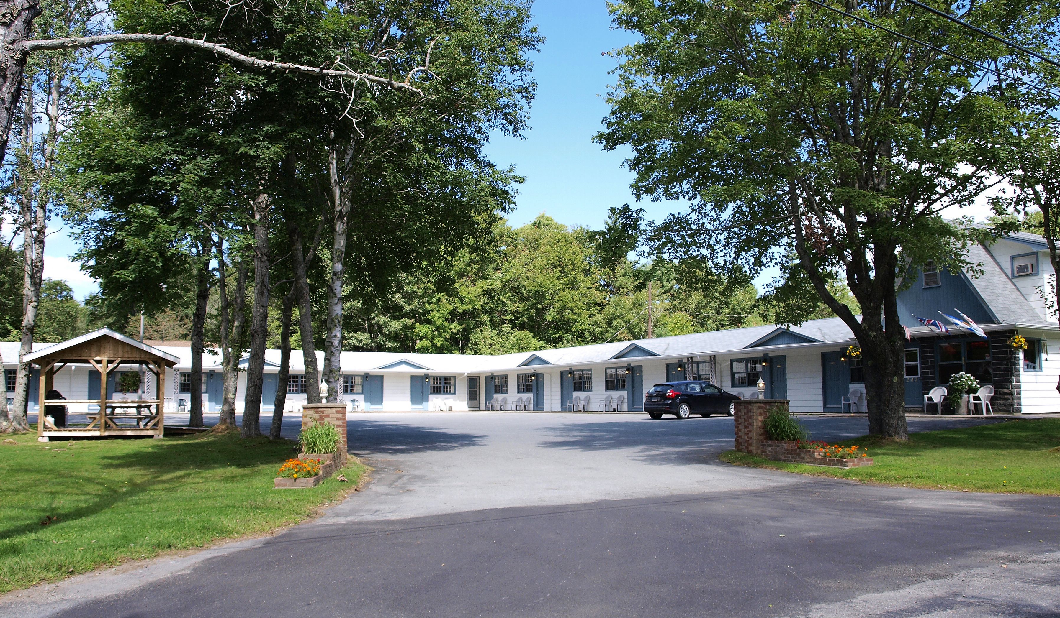 A motel with a covered parking area, a picnic table, and a small garden.