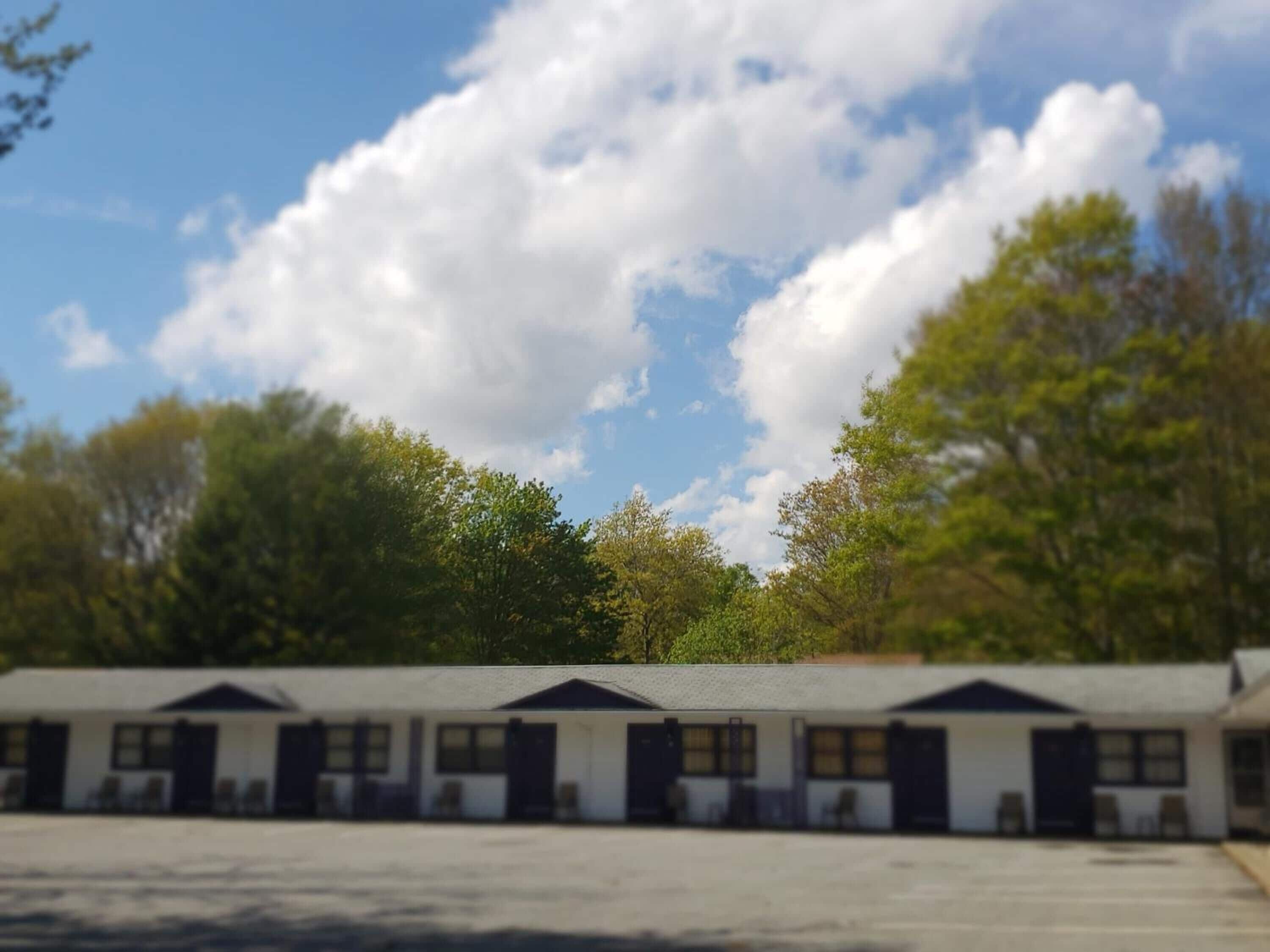 A row of motel-style buildings with a clear sky and trees in the background.