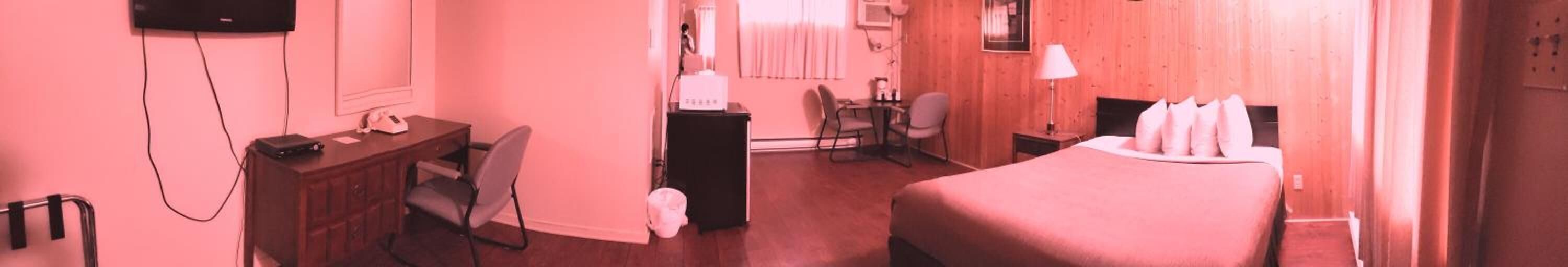Habitación de hotel con cama, escritorio, silla y televisor montado en la pared.