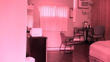 A hotel room with a bed, a desk, a chair, a TV, and a window with curtains.