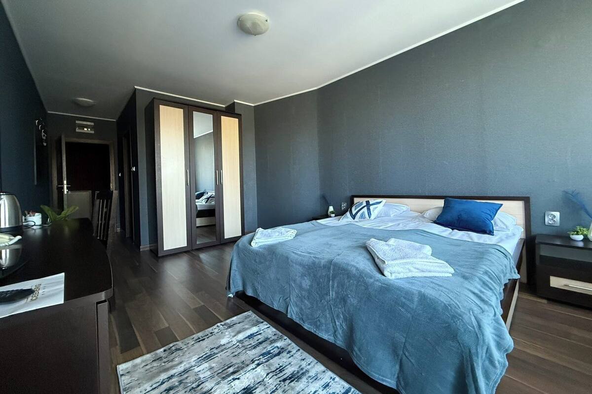 A modern bedroom with a large bed, a wardrobe, and a desk.