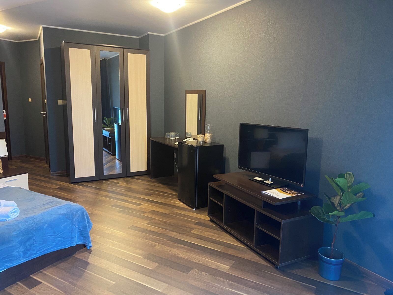 Una habitación de hotel moderna con cama, televisión, escritorio y espejo.