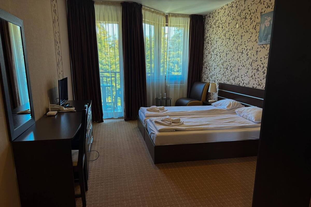 A hotel room with a bed, a desk, a chair, and a TV.