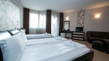Una habitación de hotel con dos camas individuales, un escritorio, un televisor, un sofá y un mueble pequeño.