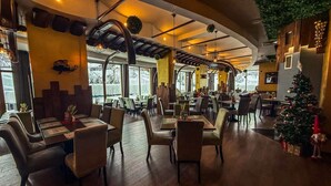 Un restaurante con suelo de madera, techos altos y un árbol de Navidad.