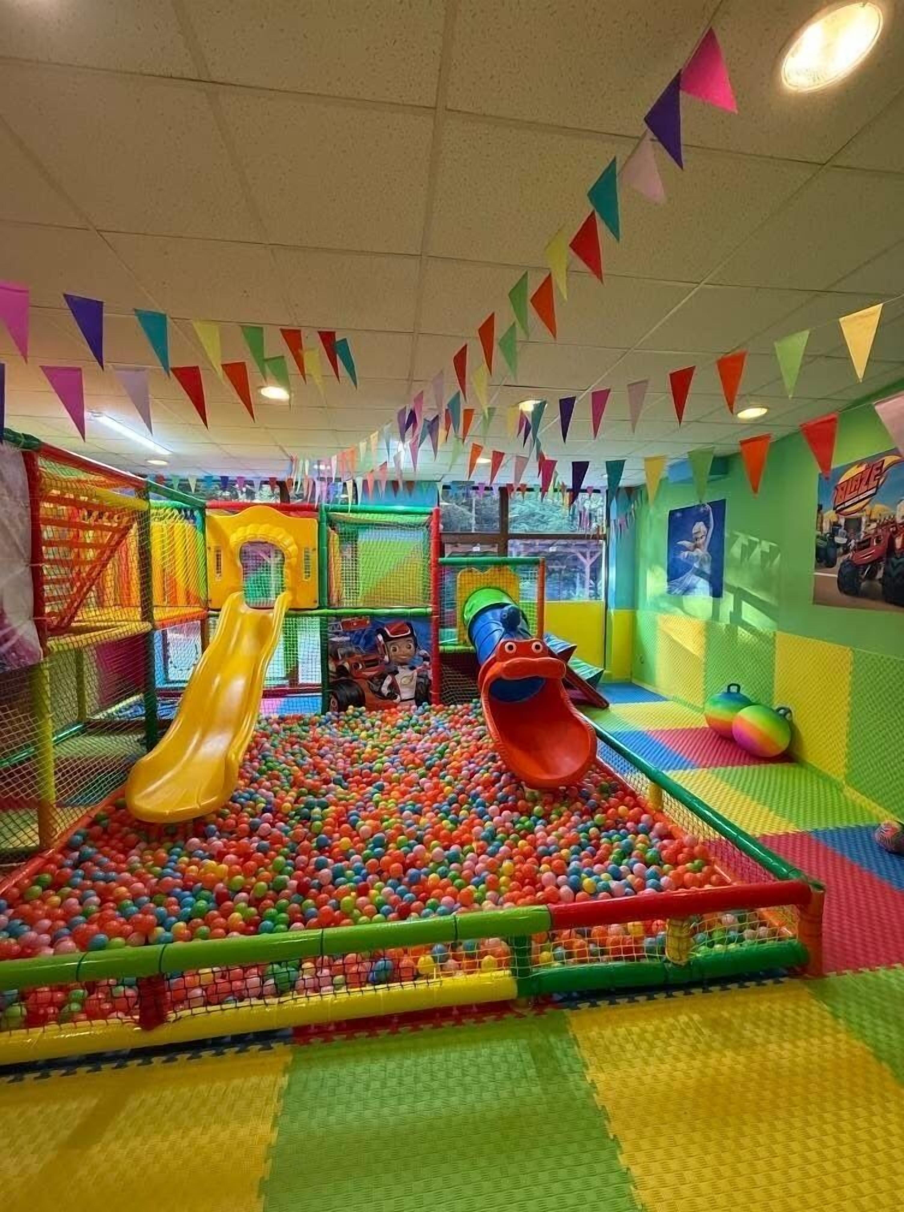 An indoor play area with slides, a ball pit, and colorful decorations.