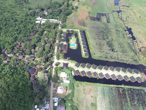 An aerial view of a residential area with houses, a swimming pool, and a canal.