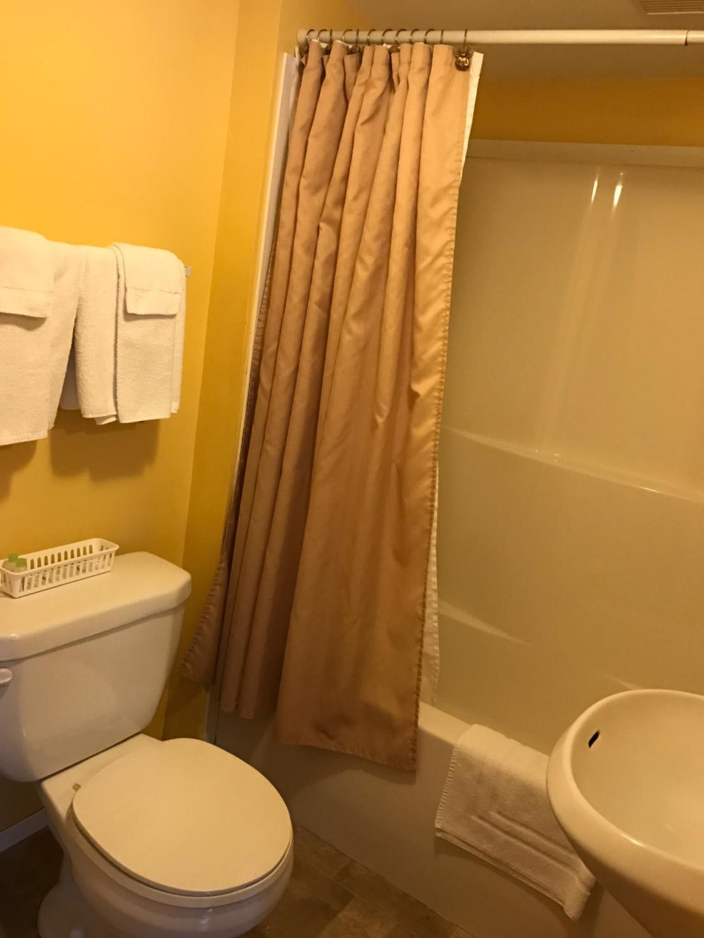 Un baño con inodoro, lavamanos y cortina de ducha.