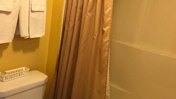 Un baño con inodoro, lavamanos y cortina de ducha.