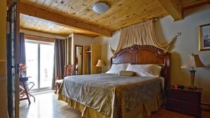 Un dormitorio con una cama grande, techo de madera y vista a través de un ventanal.
