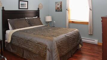A bedroom with a large bed, a nightstand, a lamp, and a window with curtains.
