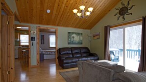 Un espacio habitable amplio con piso de madera, un sofá de cuero, un sofá marrón y una mesa de comedor.