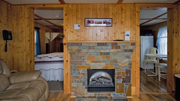 Una habitación acogedora con chimenea de piedra, paredes de madera, una cama y un comedor.