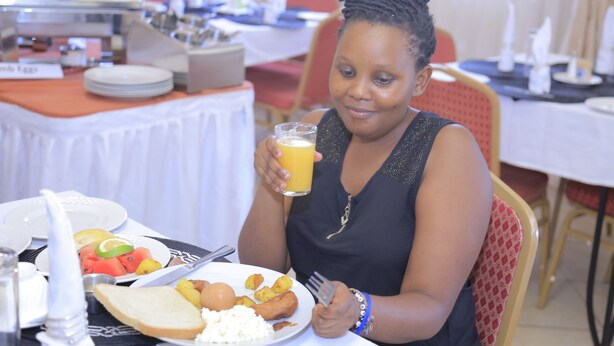 A dining area with a buffet setup, including plates of food and a glass of orange juice. - Executive Airport Hotel (Entebbe)
