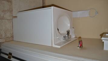 Una lavadora blanca en un baño con pared color crema y suelo de mármol.