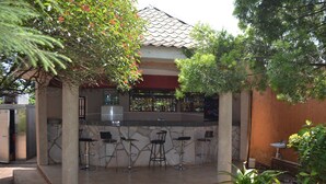 An outdoor bar area with a stone counter and four bar stools. - Executive Airport Hotel (Entebbe)