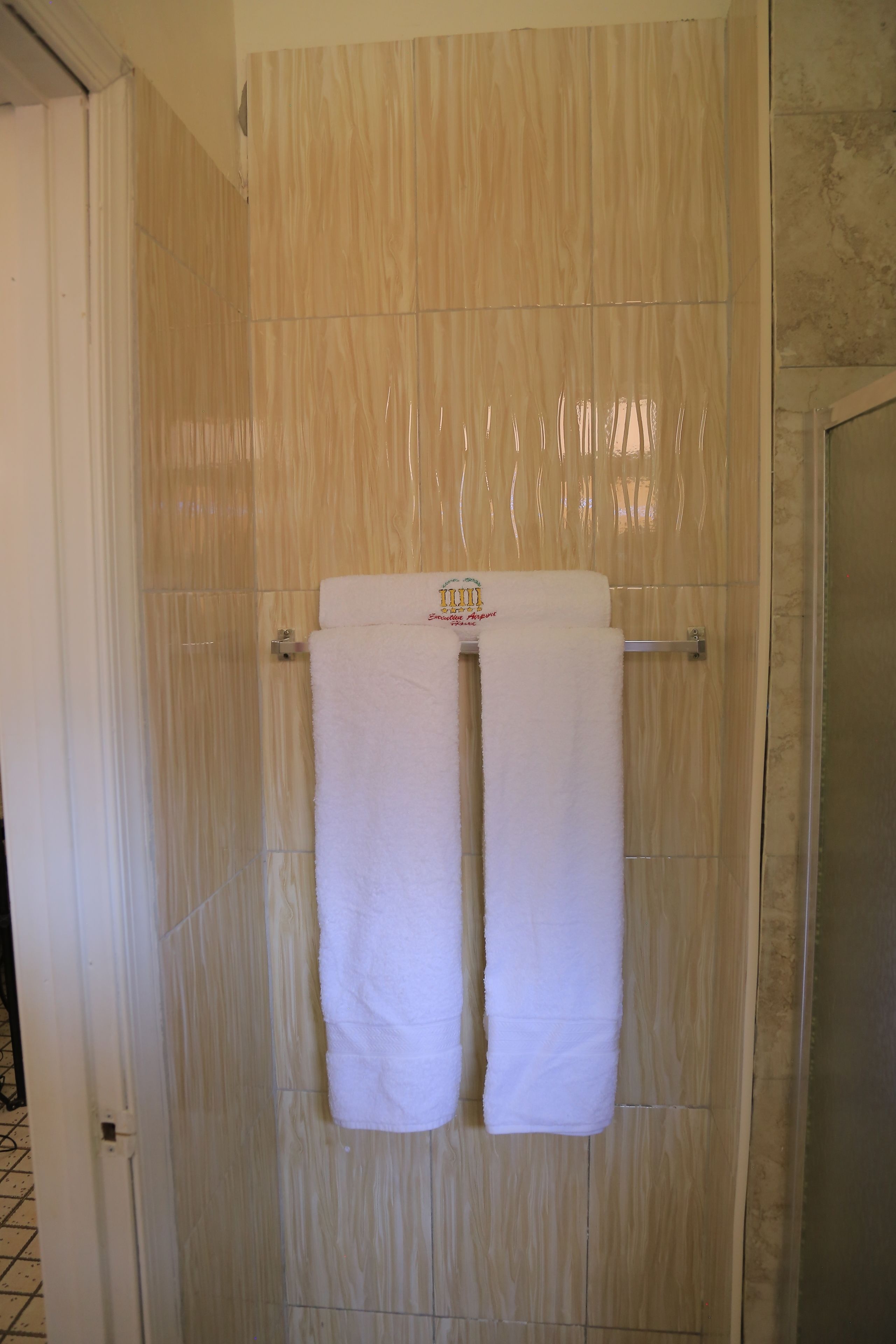 Une salle de bain avec des murs recouverts de carreaux beiges et un espace douche.