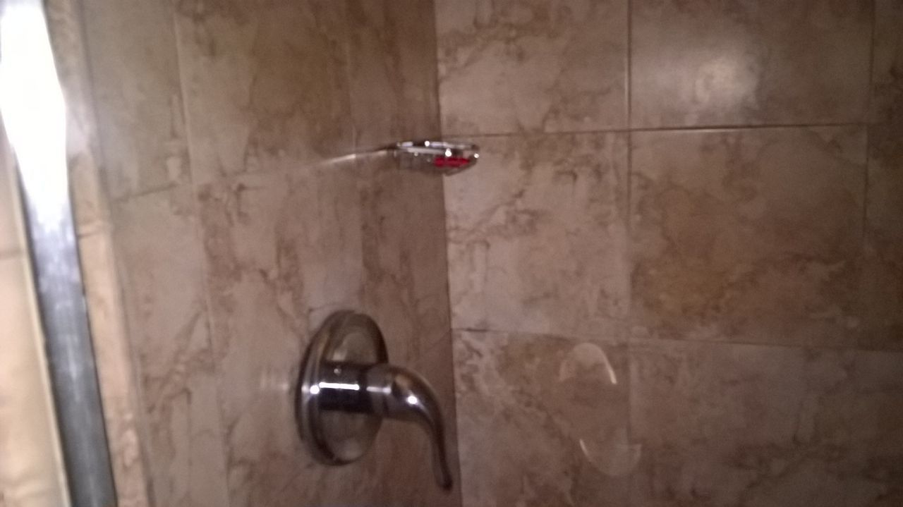 Une salle de bain avec un mur en marbre, une porte de douche et un robinet.