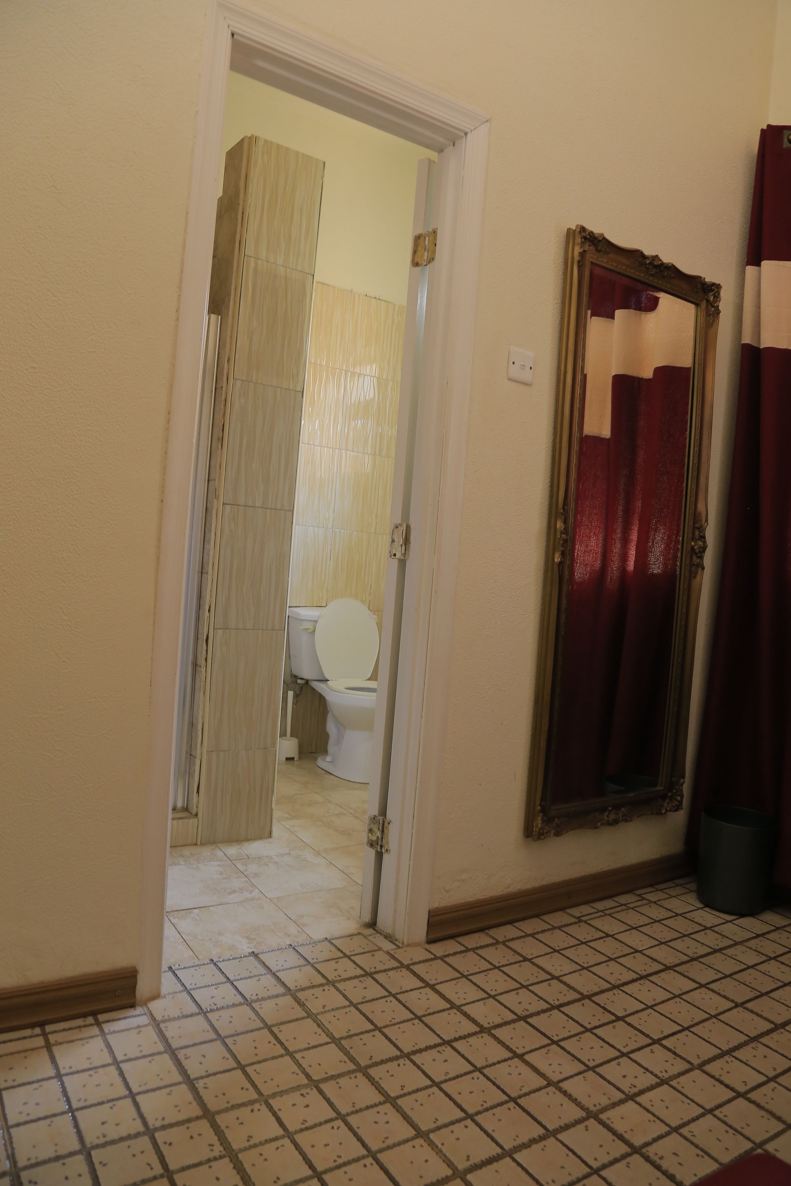 Une salle de bain avec des toilettes, un miroir et un sol carrelé.