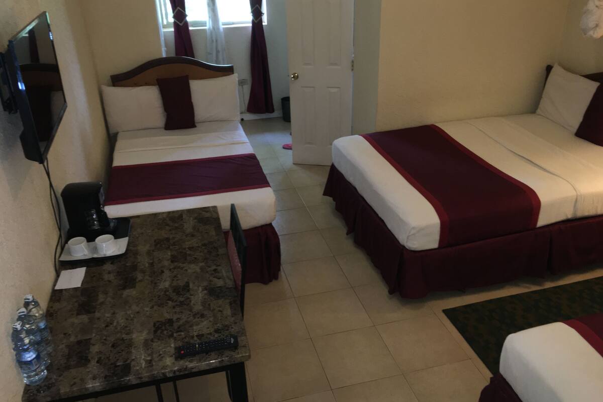 A hotel room with two beds, a small table, and a TV.