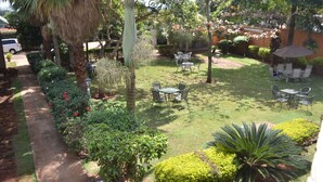 A well-maintained garden with a paved walkway, outdoor seating area, and various plants. - Executive Airport Hotel (Entebbe)