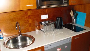 A compact kitchen with a stainless steel sink, a toaster, a kettle, and a microwave. - Apartamentos La Pleta Incles Suites 3000 (Soldeu)